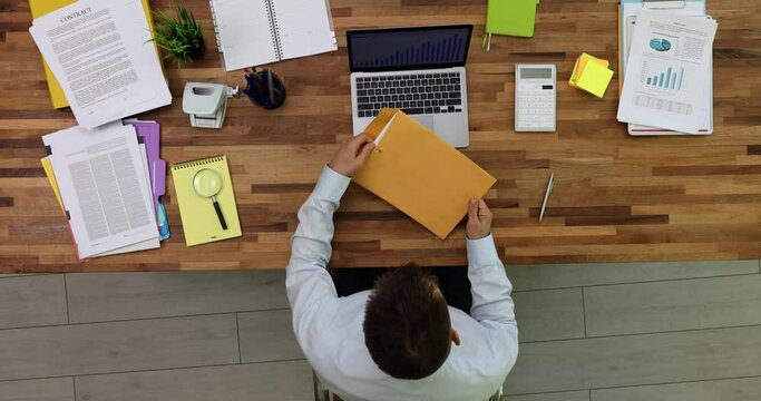 Receiving news by mail man holds in hands paper letter with refusal, top view. Businessman takes message out of envelope and reads information from bank client supplier