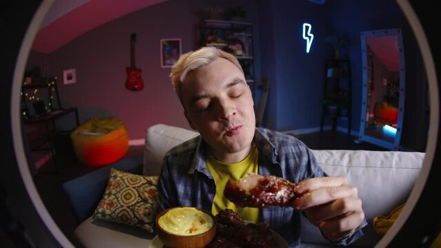 Food streamer eating chicken for video. Eating food live, shares impressions smiling contentedly. Review of meal from delivery, fast food restaurants. Mukbang stream for social media subscribers likes