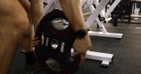 Removing weight plates from deadlift barbell in gym. Strength training and barbell weight selection