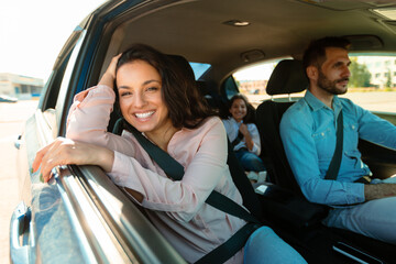 Happy family in car, woman smiling to camera sitting on passenger seat, enjoying trip by their new...