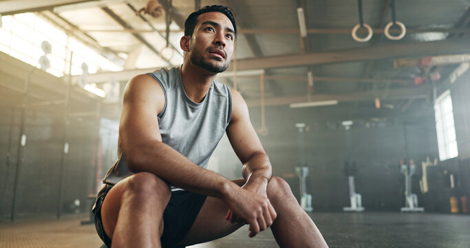 Fitness, breathing and sweating with a tired man in the gym, resting after an intense workout. Exercise, health and fatigue with a young athlete in recovery from training for sports or wellness - Powered by Adobe
