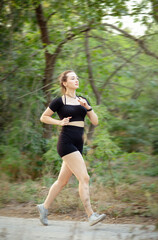 young woman running in forest park. Girl jogging at sunset on nature, health and sport concept