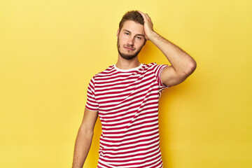 Young Caucasian man on a yellow studio background tired and very sleepy keeping hand on head.