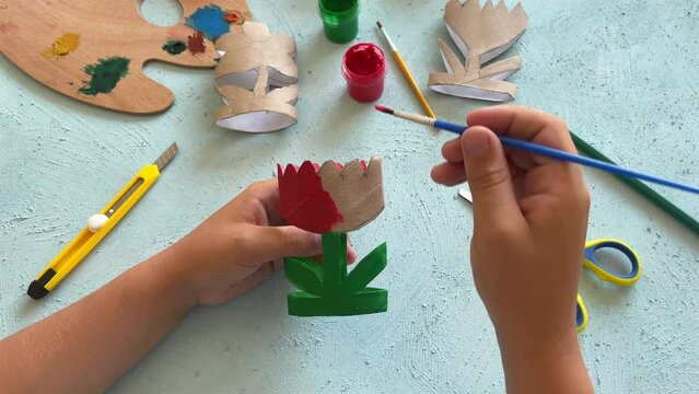 DIY and creativity. A close-up of children hands, which are painted with a flower cut out of a cardboard roll with a brush.
