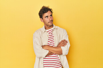 Young Latino man posing on yellow background dreaming of achieving goals and purposes