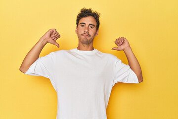 Young Latino man posing on yellow background feels proud and self confident, example to follow.