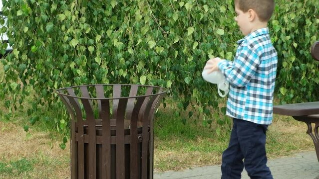 Little boy throws a biodegradable disposable bag of biomaterials in the trash.