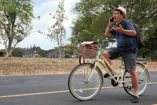 Asian tourist stopping his bicycle at Prambanan temple national park to ask for direction, 21 September 2023
