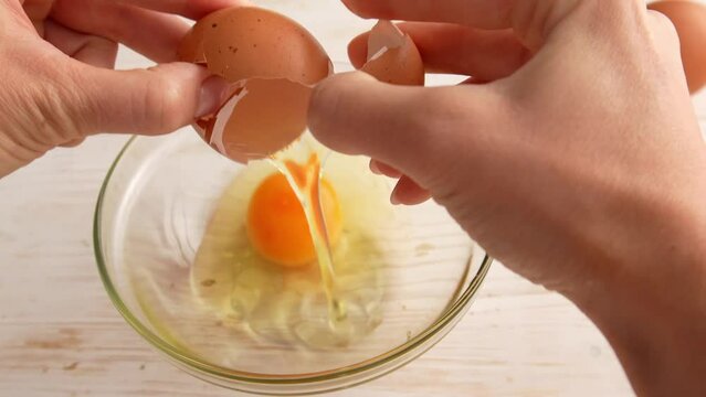 Female hands break eggs into a bowl. Cooking food.