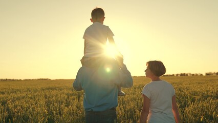 teamwork. child sits on his father's shoulders rides. happy family in the wheat field. family...