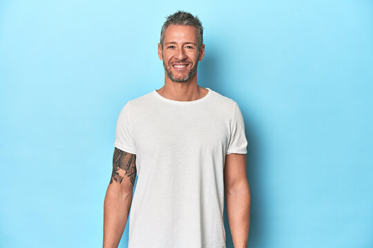 Middle-aged man posing on blue studio backdrop