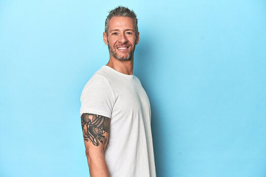 Middle-aged man posing on blue studio backdrop