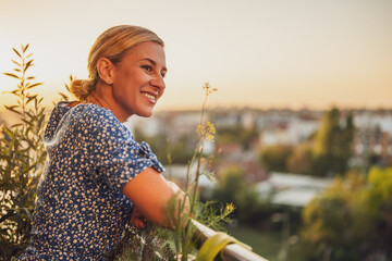 Beautiful woman enjoys  standing on her balcony at sunset.