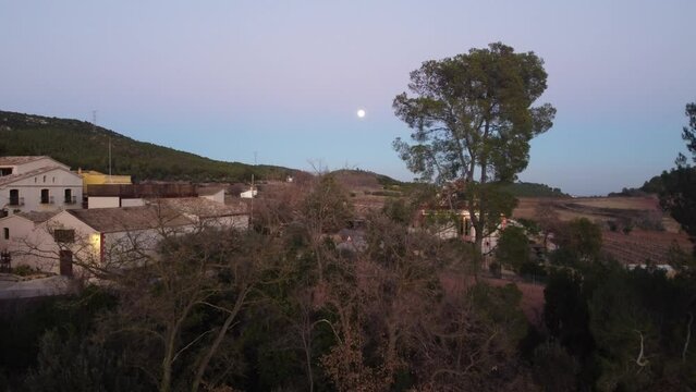 Moon views during a sunset over a rural village