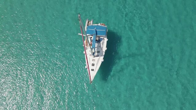 Aerial top view video of a boat in the crystal clear sea water