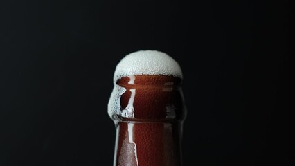 Hand putting beer bottle with froth, close-up