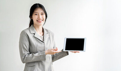 young smiling asian woman worker showing black screen digital tablet, standing over white background.