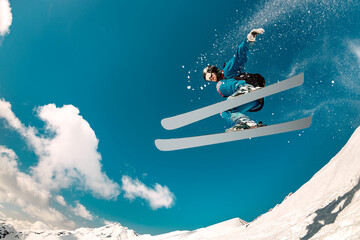Fast young skier jumps and fly in cloud of powder snow. Winter sports at ski resort - obrazy, fototapety, plakaty