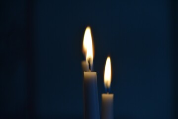 Closeup shot of two lit candles slowly burning in a dark room - Powered by Adobe
