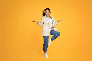 Fototapeta na wymiar Cheerful young asian woman in jacket jumping, freezes in air, have fun, enjoy great mood, free time