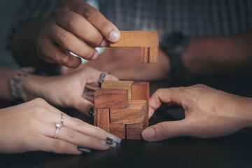 Business peoples putting connect model wooden jigsaw puzzle. Team work and strategic solution concept. Selected focus