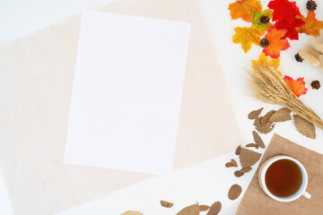 Naklejka na ściany i meble Modern office desk with coffee cup, notebook, yellow-red autumn leaves on white background with copy space. Place for your text. Work table with office supplies. concept cosy, cozy, seasonal autumn