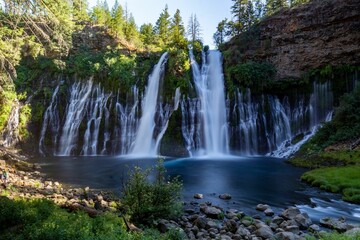 Fototapeta na wymiar Landscape of Burney Falls surrounded by greenery on a sunny day in California