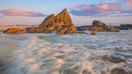 Burst of bright sunshine illuminating the rocky shoreline of an idyllic beach