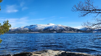 Scenic view of snowy mountains near a lake on a sunny day in Norway