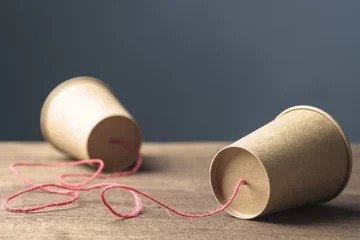 Fotobehang Two brown paper cups with string as old style or toy phone, two way communication © patpitchaya