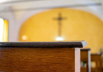 Dark brown church pews with light yellow background of altar and crucifix