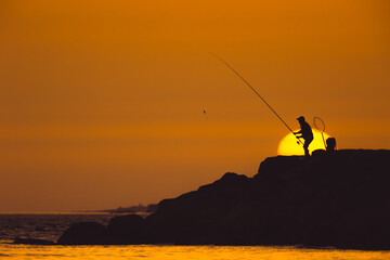 Fototapeta na wymiar A man is fishing at sunset