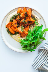Vegan lunch - hummus, baked sweet potato and pesto, white background.