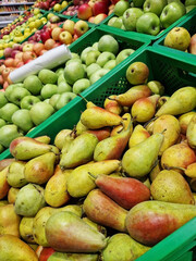 Apples and pears in plastic boxes in a store, close-up. Ripe apples for sale, side view. Selling fruits