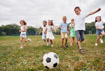 Soccer ball, playing together. Kids are having fun on the field at daytime