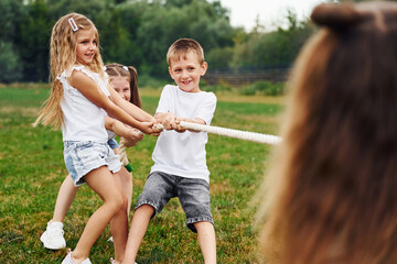 Playing tug of war game. Kids are having fun on the field at daytime together