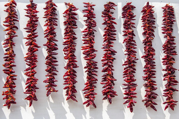 Assortment of chili peppers from Espelette France hanging on exterior of building 