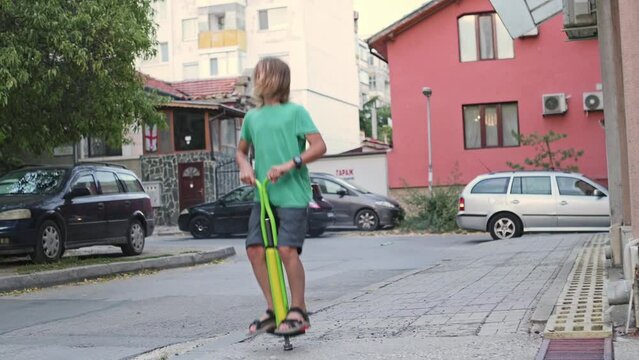 A boy joyfully performs tricks on a pogo stick, experiencing excitement and happiness