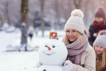 Young blonde woman building snowman at the park in winter