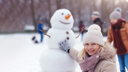 Young blonde woman building snowman at the park in winter