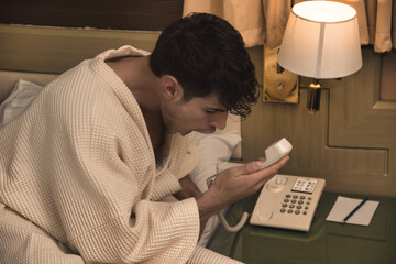 A man in a bathrobe using a phone, screaming into it in frustration or anger