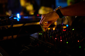 A close-up of the DJ's hand on the mixer console in a nightclub, crafting music and dance ambiance.