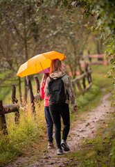 Mother and daughter walking in the rain on an early autumn day. 