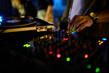 A close-up of the DJ's hand on the mixer console in a nightclub, crafting music and dance ambiance.