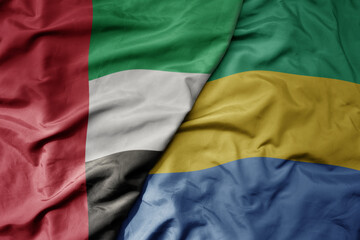 big waving realistic national colorful flag of united arab emirates and national flag of gabon .