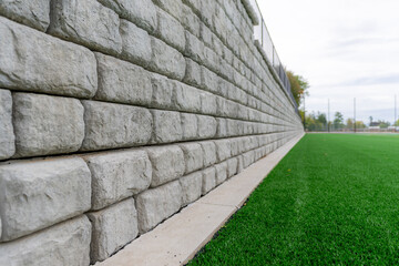 Retaining wall next to a green synthetic turf athletic field.