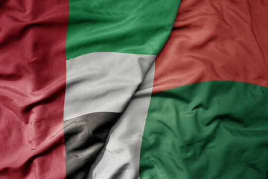 big waving realistic national colorful flag of united arab emirates and national flag of madagascar .
