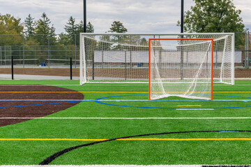 Photo of a lacrosse goal on a empty green synthetic turf field.	