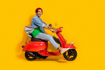 Full size photo of nice young guy driving red vintage scooter moped excited wear trendy jeans...