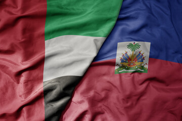 big waving realistic national colorful flag of united arab emirates and national flag of haiti .